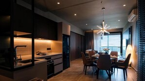 A modern kitchen with a dining area, featuring a built-in oven, a sink, and a dining table with chairs. - Antara Genting by Harvinton Mansion (Bentong)