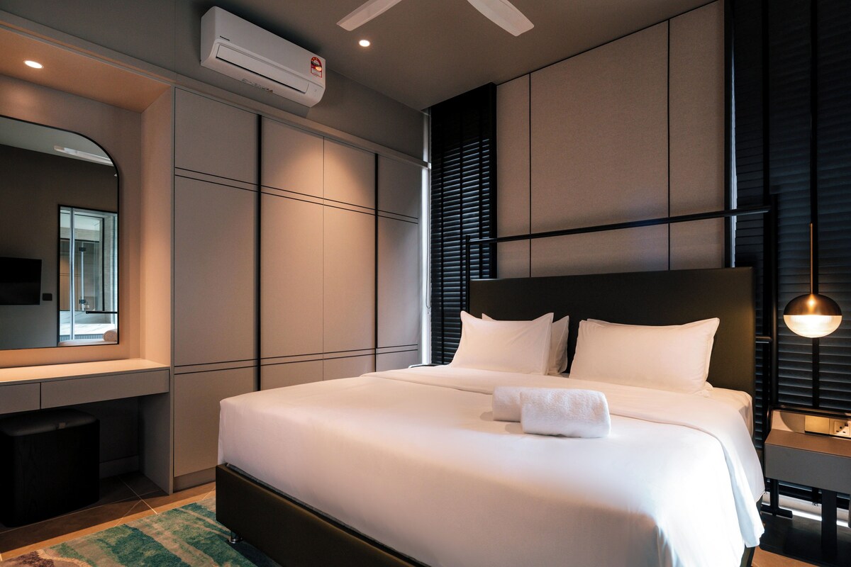 Una habitación de hotel moderna con una cama grande, un escritorio integrado, un espejo y una ventana con persianas.