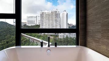 Un baño con bañera, una ventana que ofrece vistas a la ciudad y una pared de madera.