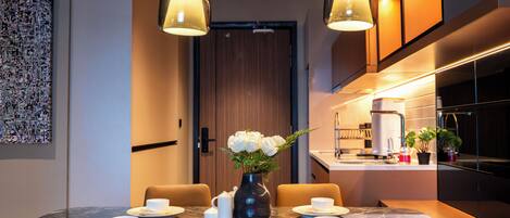 A modern dining area with a marble table, two pendant lights, and a vase with white flowers.