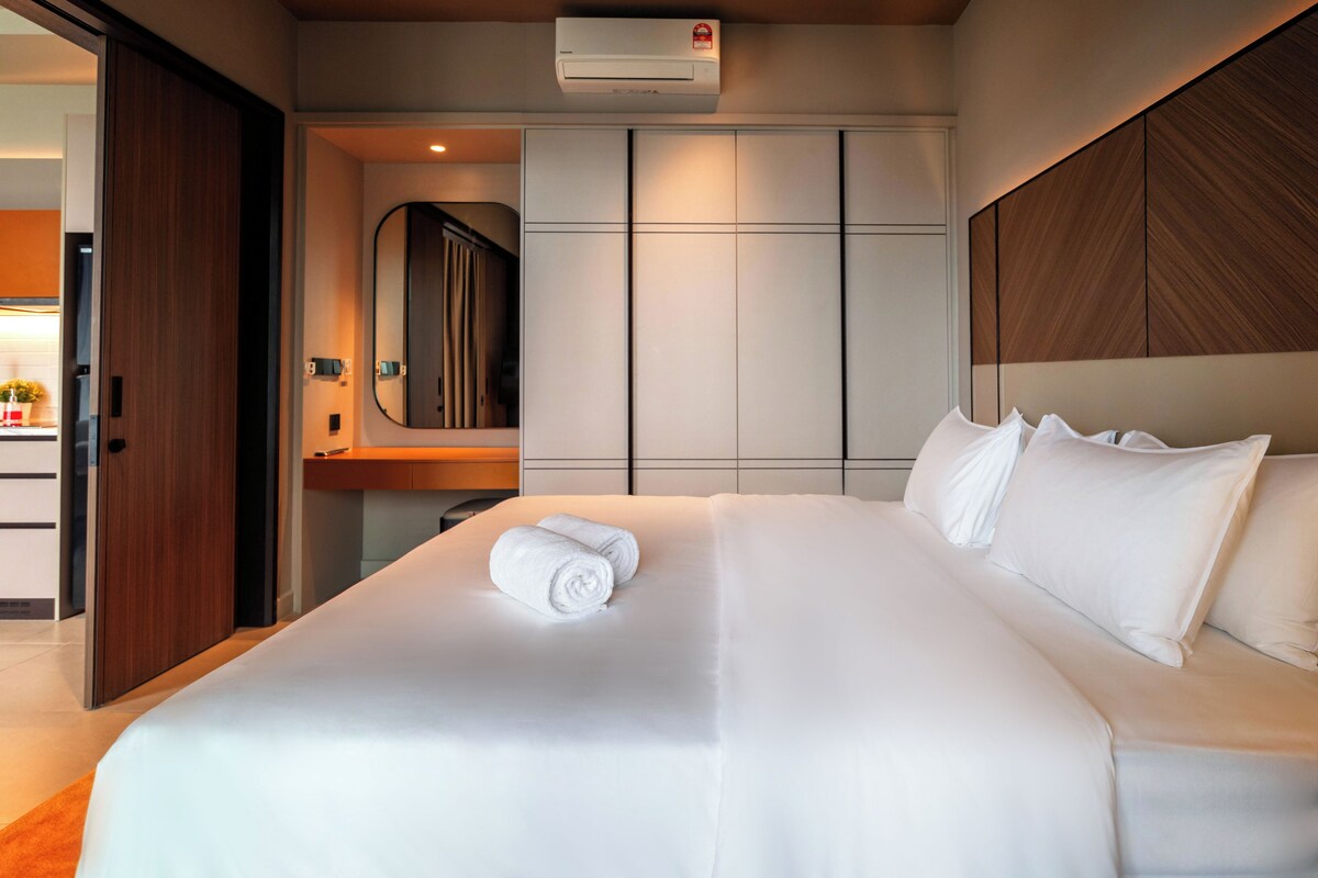 Una habitación de hotel con una cama grande, cabecera de madera, un espejo y un armario.