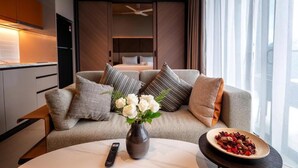 A modern hotel room with a sofa, a vase of flowers, a remote control, and a plate of food on a table. - Antara Genting by Harvinton Mansion (Bentong)