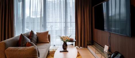 A modern living room with a sofa, a coffee table, a vase with flowers, a flat-screen TV, and a telephone.