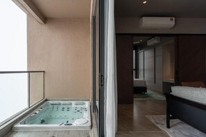 A balcony with a hot tub, a sliding glass door, and a view of the interior.
