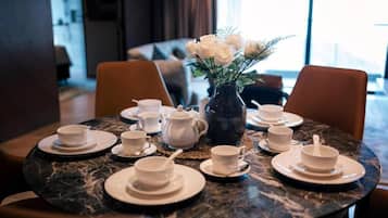 Een eettafel gedekt met witte kopjes en schotels, een vaas met witte bloemen en een tafelblad van marmer.