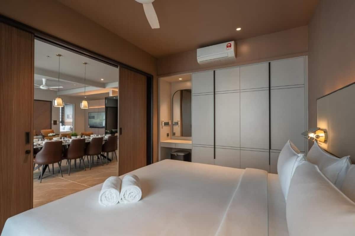 Habitación de hotel con cama, zona de comedor, espejo y unidad de aire acondicionado.
