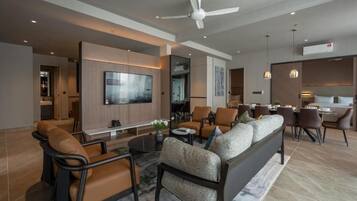 A modern living room with a sofa, chairs, a TV, and a dining area.