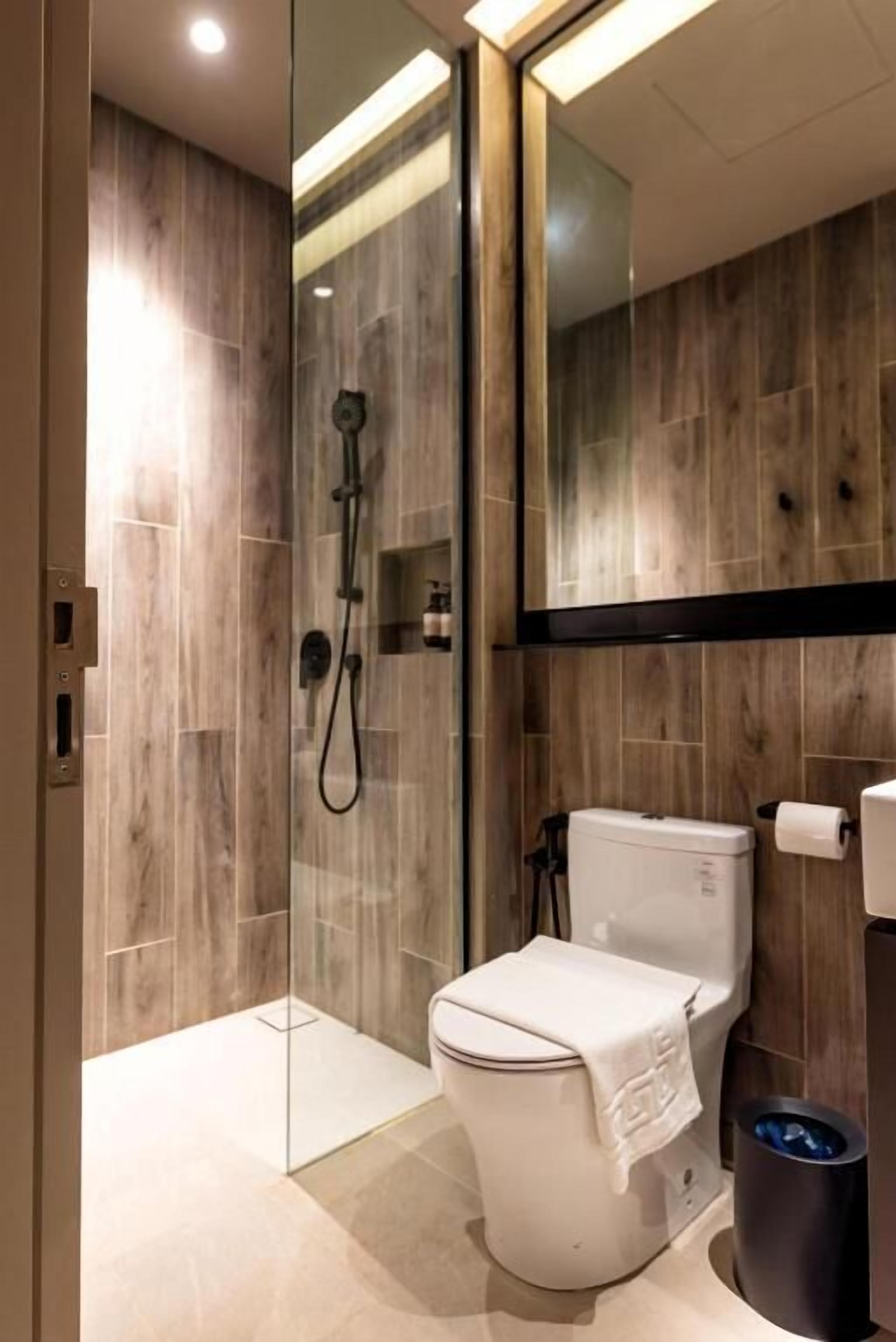 A modern bathroom with a glass-enclosed shower, a toilet, and a bidet.
