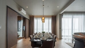 A modern dining area with a long table set for a meal, surrounded by chairs, with a pendant light above. - Antara Genting by Harvinton Mansion (Bentong)