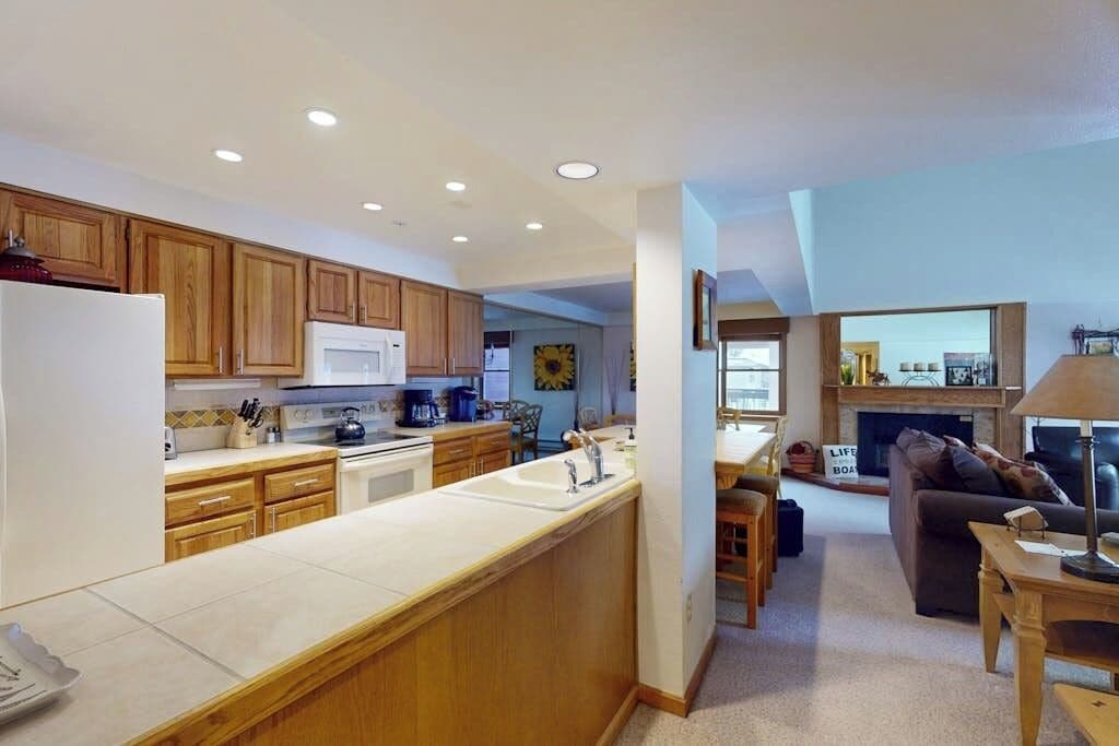 A modern kitchen with wooden cabinets, a white refrigerator, and a built-in island with a sink.