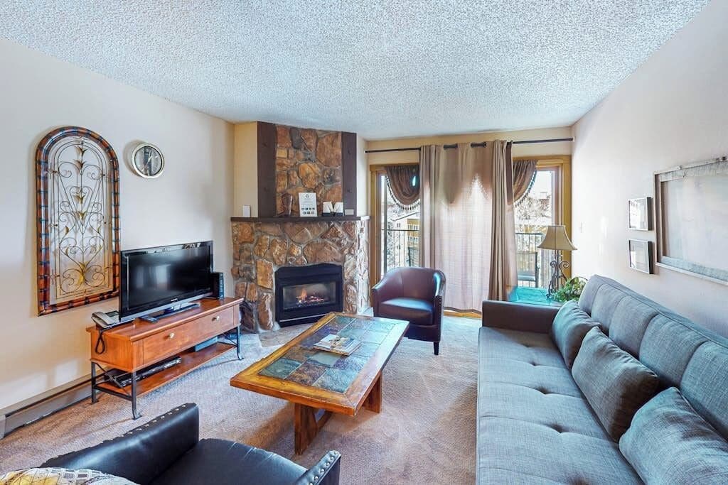 Een woonkamer met een open haard, een televisie, een bank en een salontafel.