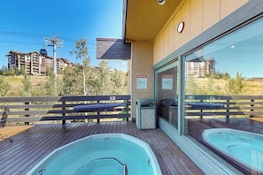 Ein Wellnessbereich mit zwei Whirlpools, einer Holzdiele und Blick auf umliegende Gebäude.