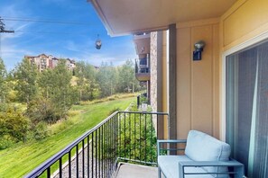 Ein Balkon mit Blick auf eine grüne Landschaft und entfernte Gebäude.