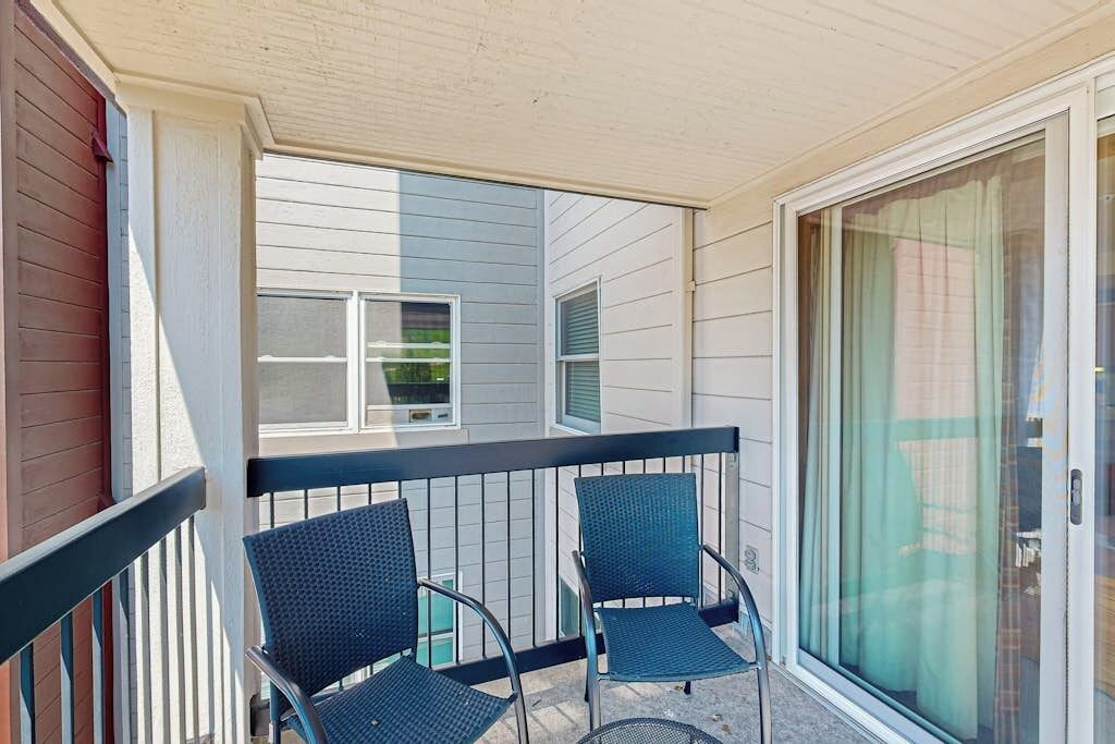 A balcony with two chairs and a glass door.