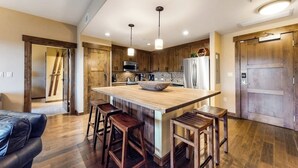 Une cuisine moderne dotée d’un îlot central, de tabourets de bar, de meubles en bois et d’un réfrigérateur.