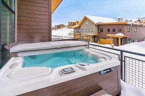 Ein Whirlpool auf einem Balkon mit Blick auf schneebedeckte Gebäude.