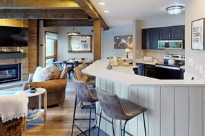 Eine moderne Küche mit Bar, Kamin und Essbereich mit einer Couch und Stühlen.
