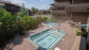 Ein Poolbereich auf dem Dach mit Whirlpool, Gartenmöbeln und Blick auf die umliegenden Gebäude.