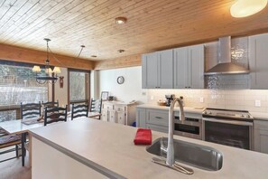 Eine moderne Küche mit einer großen Kochinsel, Edelstahlgeräten und einer Holzbalkendecke.