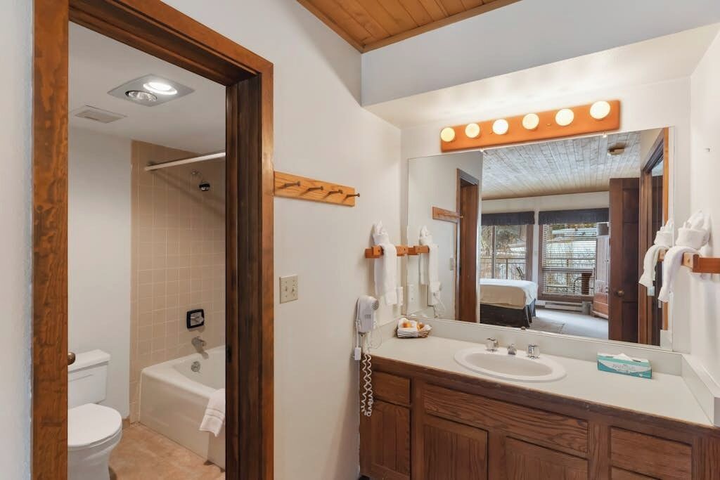 A bathroom with a bathtub, toilet, vanity with a mirror, and a towel rack.