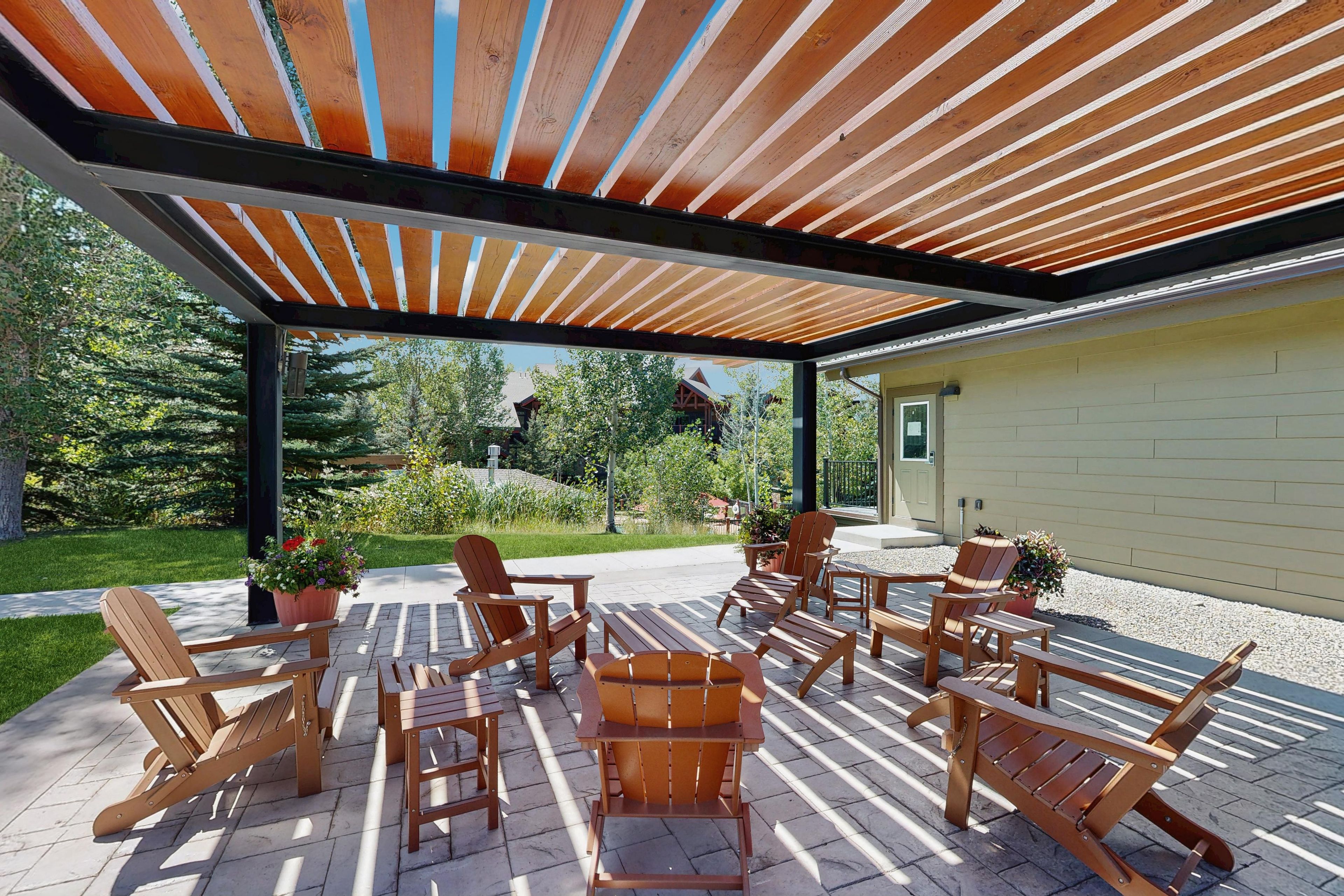 An outdoor patio with wooden furniture and a wooden pergola.