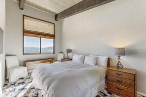 A bedroom with a large bed, a bedside table with a lamp, a chair, and a window with a view. - Amazing Ski-In/Out Condo w/Balcony, Free WiFi, Fireplace, Shared Hot Tub, Pool (Steamboat Springs)
