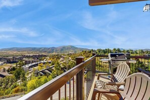 A balcony with a view of a residential area, a grill, and Adirondack chairs. - Amazing Ski-In/Out Condo w/Balcony, Free WiFi, Fireplace, Shared Hot Tub, Pool (Steamboat Springs)