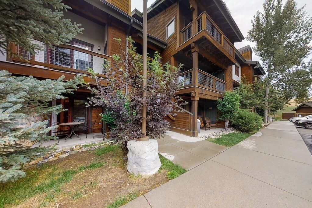 A multi-story building with balconies, outdoor seating, and a well-maintained garden.