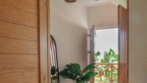 Une porte en bois qui donne sur un couloir, avec un luminaire au plafond et une plante en pot.
