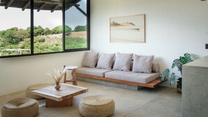 Un salon moderne avec un canapé, des poufs, une table basse et un tableau au mur.