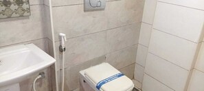 Un baño con lavamanos, inodoro y zona de ducha.