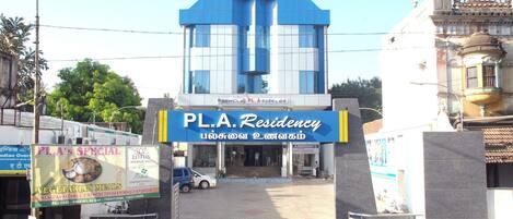 A hotel entrance with a prominent sign for PL.A. Residency, a signboard for PL.A's Special vegetarian meals, and a Lotus Marriage Hall.