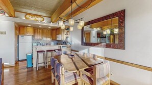 Een ruime keuken met houten kastjes, een centraal eiland en een eetgedeelte met gestreepte stoelen.