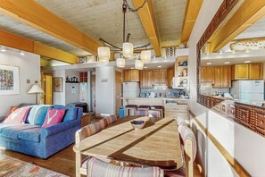 Ein großzügiger Wohnbereich mit einem Holzesstisch, einem blauen Sofa und Holzbalkendecke.