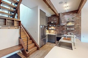 Eine moderne Küche mit Ziegelwand, Edelstahlgeräten und einer Holztreppe.