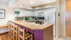 Una cocina moderna con una isla central, taburetes de bar y electrodomésticos integrados.