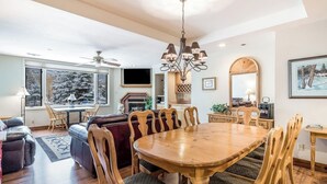 Un amplio salón con una mesa de comedor de madera, asientos cómodos, una chimenea y ventanas grandes.