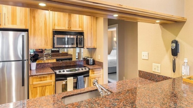 A kitchen with granite countertops, stainless steel appliances, wooden cabinets, and a built-in microwave. - Two-story condo with ski view, pool, hot tub & gas fireplace - ski/walk to lifts (Steamboat Springs)