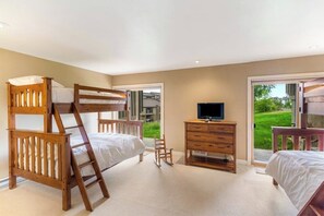 Ein Schlafzimmer mit Etagenbetten, einem Fernseher, einer Holzkommode und einer Schiebetür zu einem Balkon.