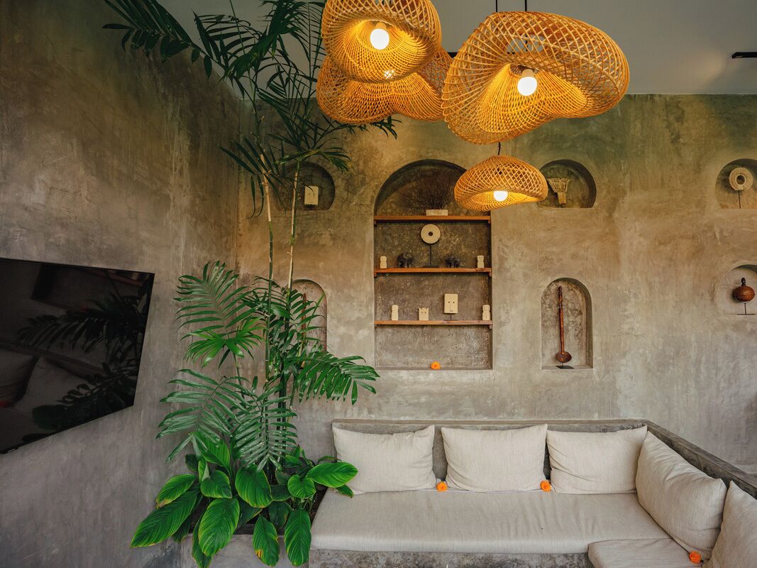 A room with a sofa, hanging wicker lamps, and a plant.
