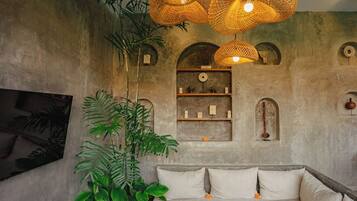 A room with a sofa, hanging wicker lamps, and a plant.