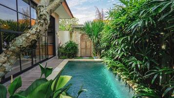 A swimming pool surrounded by lush greenery and a modern building with large windows.