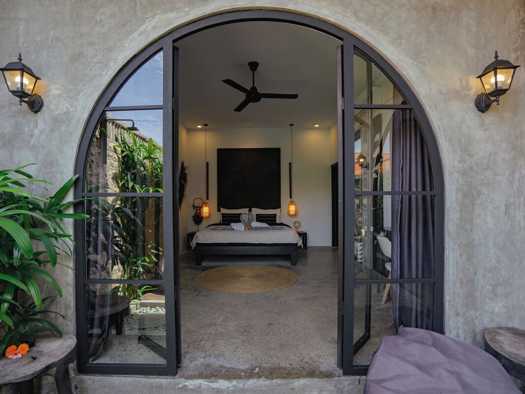 A bedroom with a bed, ceiling fan, and two wall-mounted lamps.