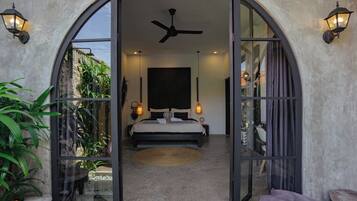 A bedroom with a bed, ceiling fan, and two wall-mounted lamps.