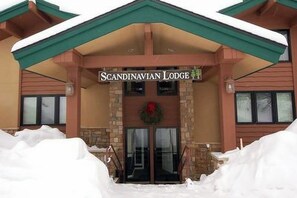 A Scandinavian Lodge building with a stone facade, a green roof, and a front entrance with a wreath.
