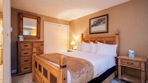 Un dormitorio con cama de madera, mesita de noche, cómoda, espejo y un cuadro en la pared.