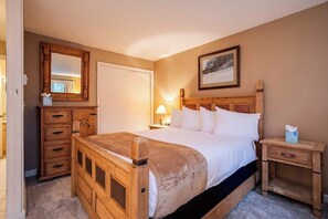 A bedroom with a wooden bed, a nightstand, a dresser, a mirror, and a picture on the wall.