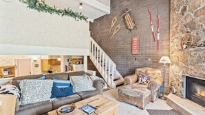Ein Wohnzimmer mit Kamin, Treppe und Skiausrüstung an der Wand.