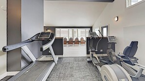 Ein Fitnessraum mit Laufbändern, einem Ergometer und einer Lounge mit Sesseln.