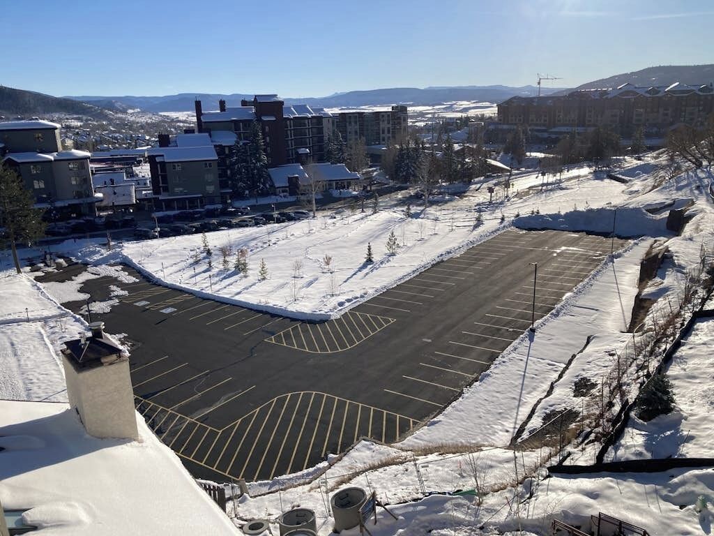 A snow-covered parking lot with buildings in the background.